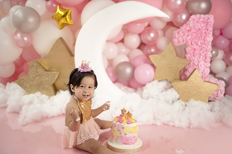 Bebé de 1 año en un estudio fotográfico con un pastel y globos